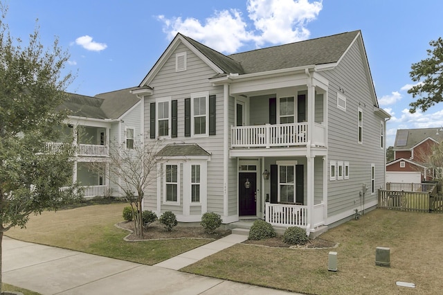 view of front of property featuring a front yard, covered porch, fence, and a balcony