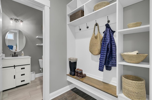 mudroom featuring baseboards, a sink, and wood finished floors