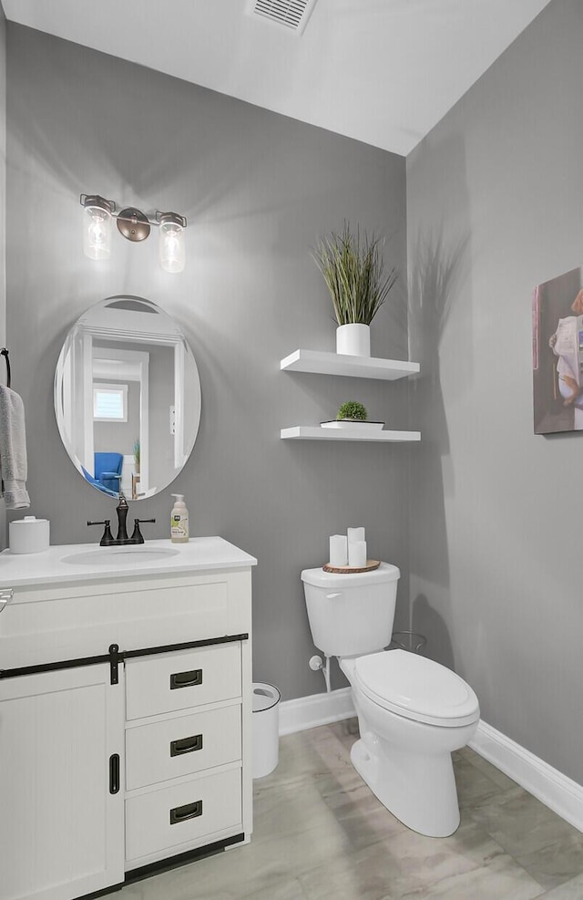 bathroom featuring toilet, visible vents, baseboards, and vanity