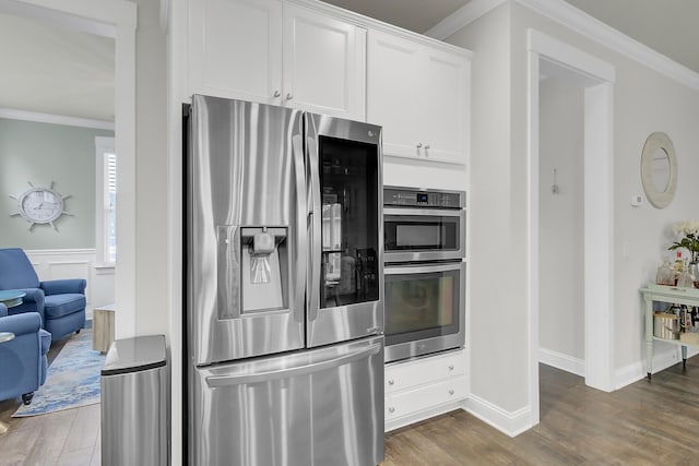 kitchen featuring appliances with stainless steel finishes, white cabinets, crown molding, and wood finished floors