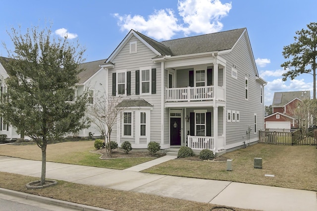 view of front of property with a balcony, covered porch, fence, and a front lawn