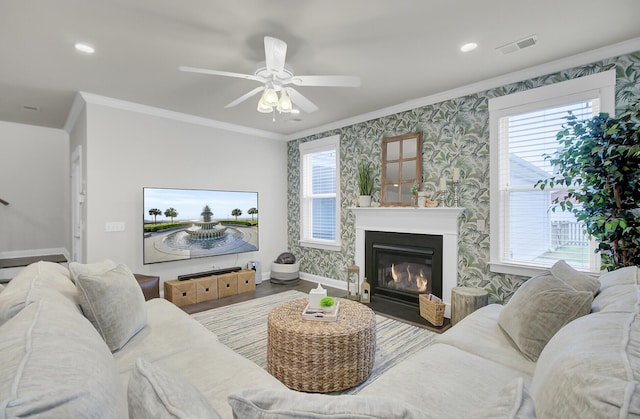 living room featuring visible vents, crown molding, baseboards, and wallpapered walls