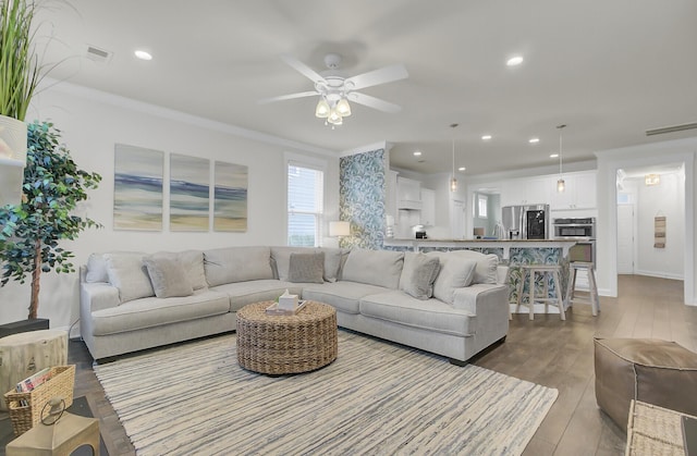 living room with recessed lighting, wood finished floors, visible vents, and crown molding