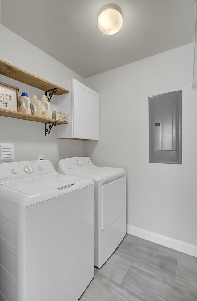 washroom featuring cabinet space, washing machine and clothes dryer, electric panel, and baseboards