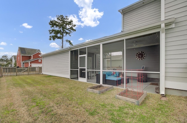 rear view of house featuring a sunroom, a garden, fence, and a lawn