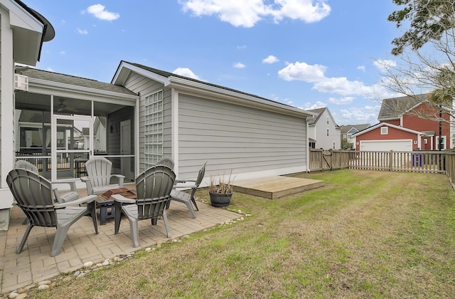 rear view of property featuring a sunroom, a patio area, a lawn, and a fenced backyard