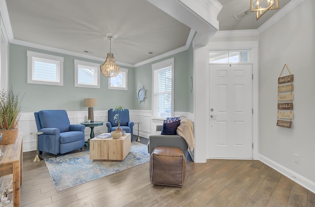 sitting room with visible vents, wainscoting, ornamental molding, wood finished floors, and an inviting chandelier