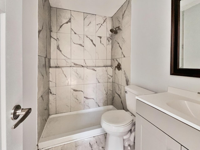 bathroom featuring a tile shower, vanity, and toilet