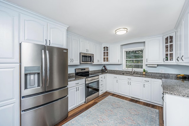 kitchen with stainless steel appliances, glass insert cabinets, dark wood-type flooring, white cabinets, and a sink