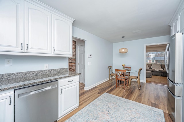 kitchen featuring baseboards, white cabinets, appliances with stainless steel finishes, light stone countertops, and light wood finished floors