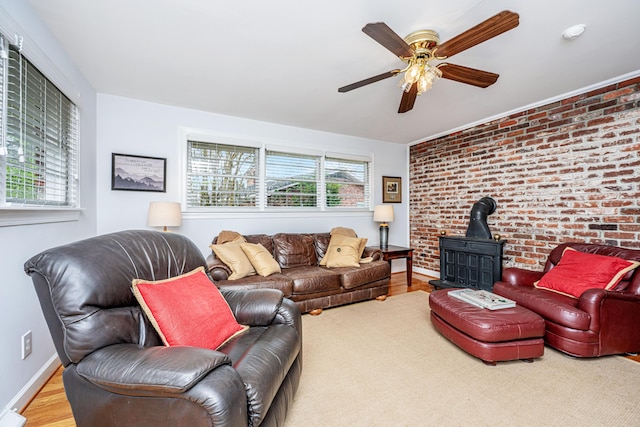 living room featuring a wood stove, a healthy amount of sunlight, brick wall, and wood finished floors