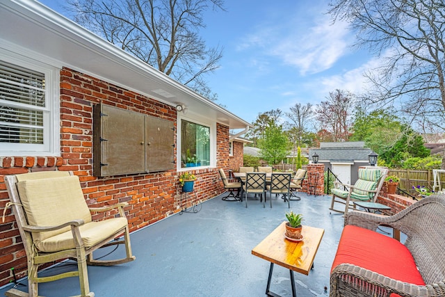 view of patio / terrace with an outbuilding, outdoor dining space, and fence