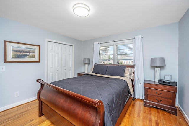 bedroom with baseboards, a closet, and light wood-style floors