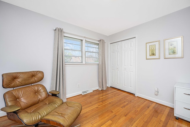 sitting room with light wood-style floors, visible vents, and baseboards