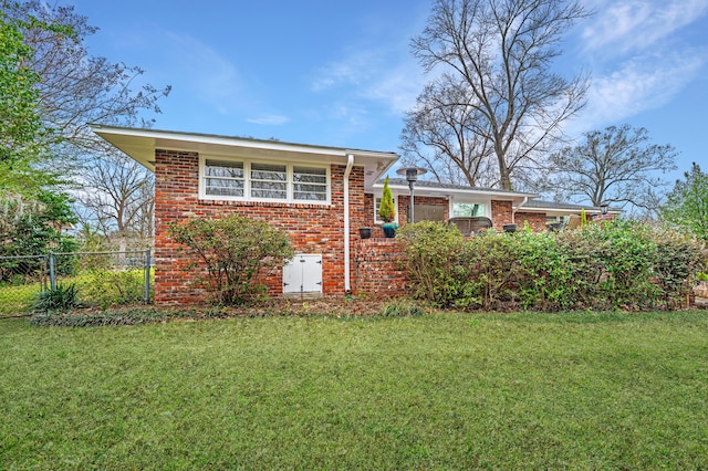 view of front of property featuring brick siding, fence, and a front lawn