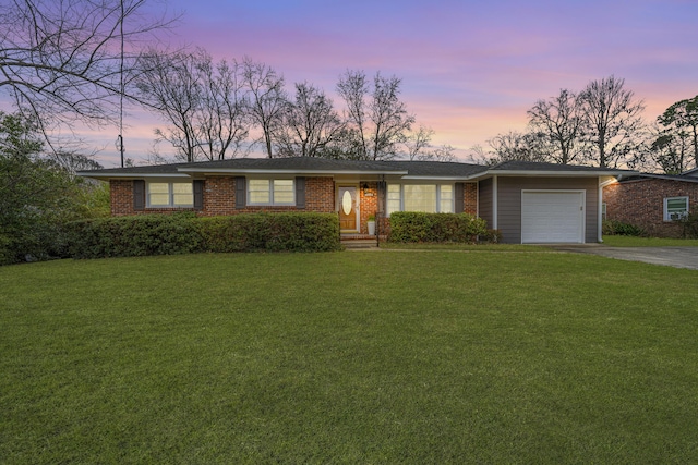 ranch-style home featuring brick siding, an attached garage, driveway, and a front lawn