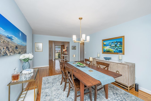 dining area with baseboards, wood finished floors, and a notable chandelier