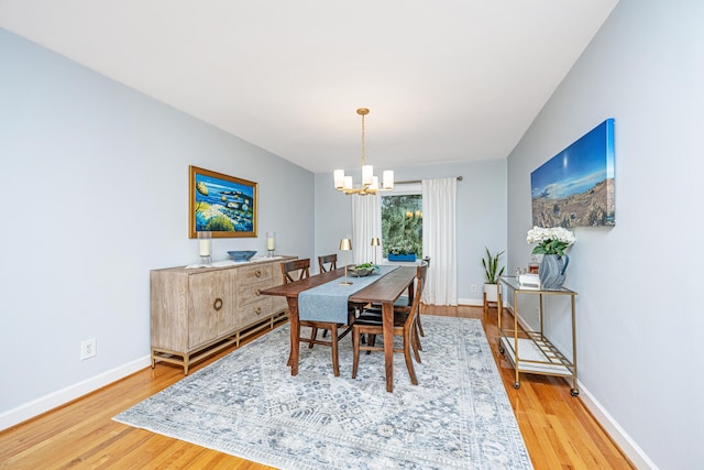 dining space with a chandelier, wood finished floors, and baseboards