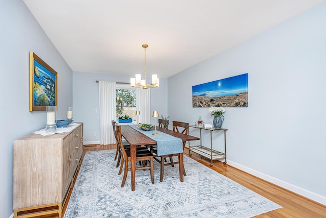 dining room with light wood-type flooring, an inviting chandelier, and baseboards