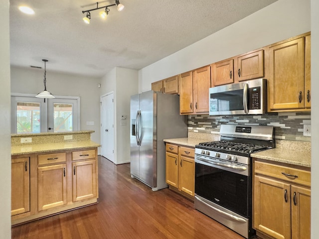 kitchen with hanging light fixtures, dark hardwood / wood-style floors, light stone countertops, appliances with stainless steel finishes, and tasteful backsplash