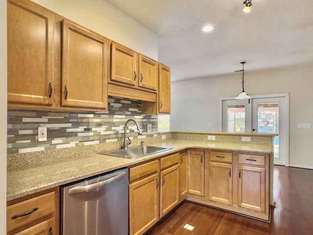 kitchen featuring dishwasher, sink, light stone countertops, decorative light fixtures, and kitchen peninsula