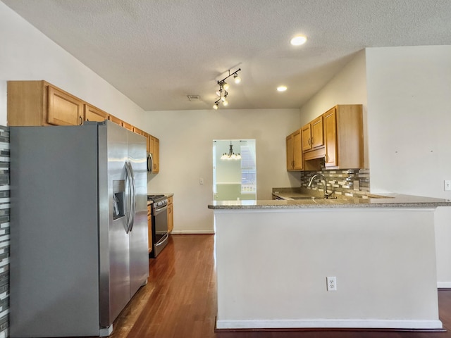 kitchen with backsplash, a textured ceiling, appliances with stainless steel finishes, dark hardwood / wood-style flooring, and kitchen peninsula