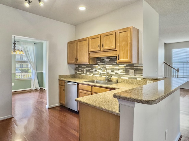 kitchen featuring backsplash, sink, stainless steel dishwasher, light stone counters, and kitchen peninsula