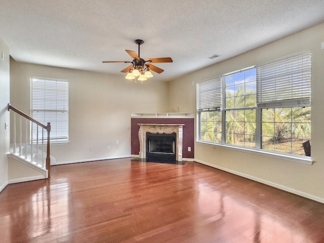 unfurnished living room with hardwood / wood-style floors, ceiling fan, a fireplace, and a textured ceiling