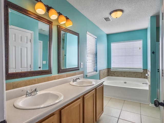 bathroom featuring a textured ceiling, tile patterned flooring, a tub, and vanity