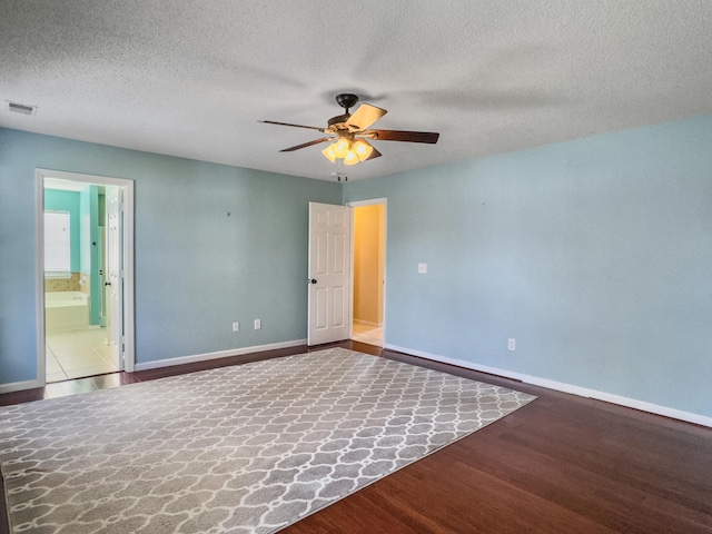 empty room with ceiling fan, hardwood / wood-style floors, and a textured ceiling