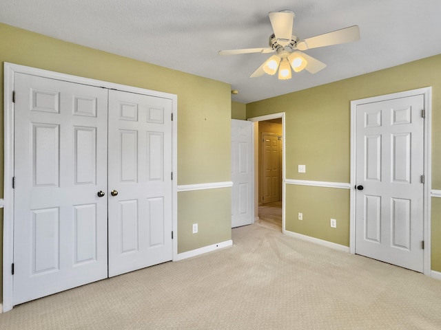 unfurnished bedroom featuring ceiling fan, light carpet, and a closet