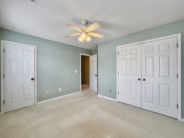 unfurnished bedroom with ceiling fan, light colored carpet, a textured ceiling, and a closet