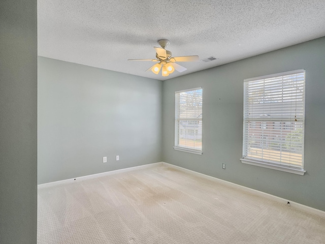 carpeted spare room featuring a textured ceiling and ceiling fan