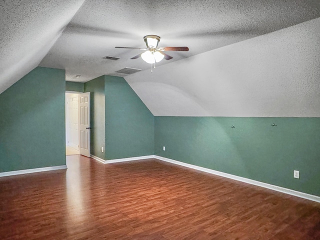 additional living space with a textured ceiling, hardwood / wood-style flooring, and lofted ceiling