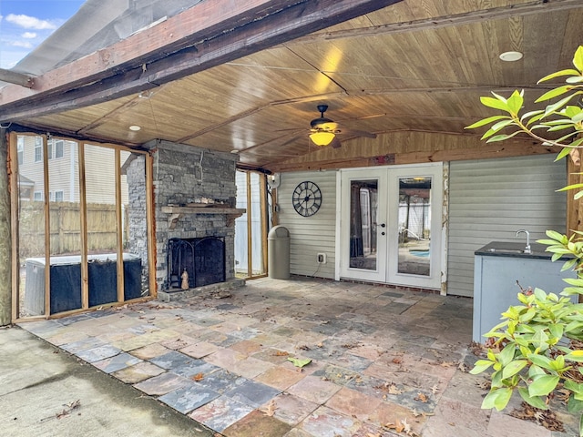 view of patio featuring an outdoor stone fireplace, ceiling fan, and french doors