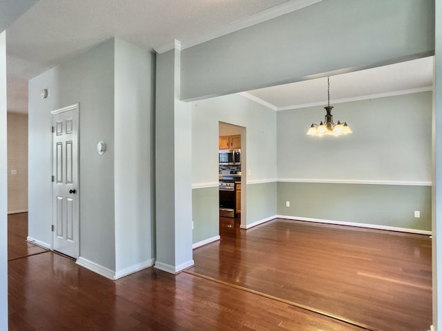 spare room with dark hardwood / wood-style flooring, ornamental molding, and a notable chandelier