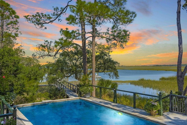 pool at dusk featuring a water view