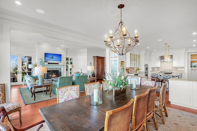 dining area with ornamental molding, a brick fireplace, plenty of natural light, and light hardwood / wood-style flooring