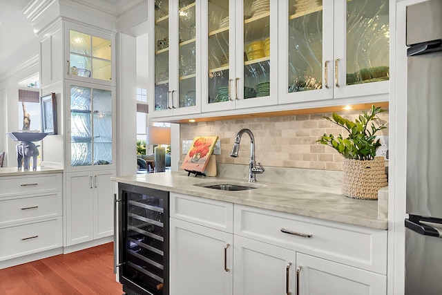 bar featuring wine cooler, sink, light stone counters, and white cabinets