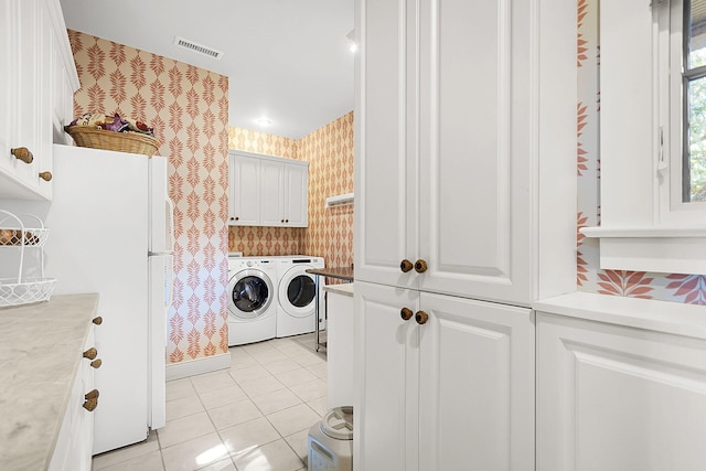 laundry area featuring cabinets, washing machine and dryer, and light tile patterned flooring