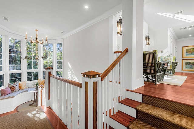 stairs with a notable chandelier, crown molding, and wood-type flooring