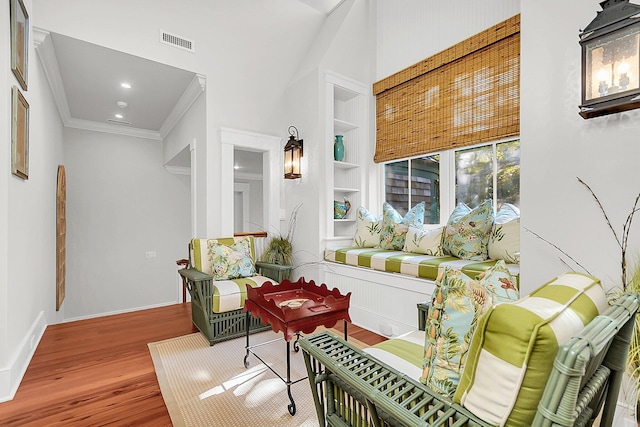 interior space featuring hardwood / wood-style flooring, ornamental molding, and built in shelves