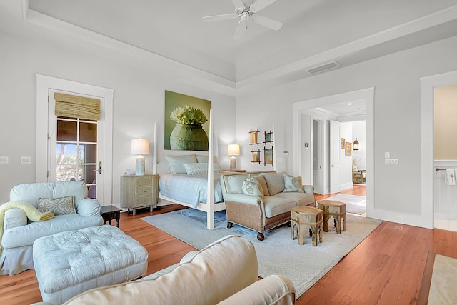 bedroom featuring a raised ceiling, wood-type flooring, and ceiling fan