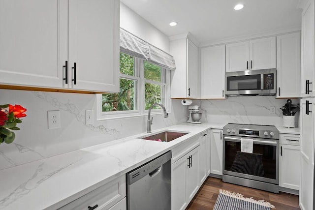 kitchen featuring light stone counters, appliances with stainless steel finishes, dark hardwood / wood-style flooring, sink, and white cabinets