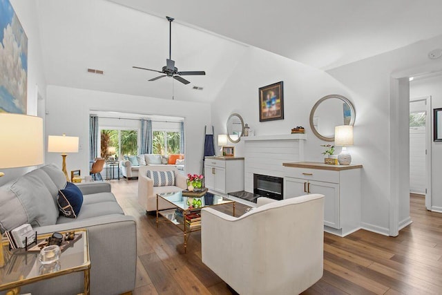 living room featuring ceiling fan, dark hardwood / wood-style floors, and vaulted ceiling