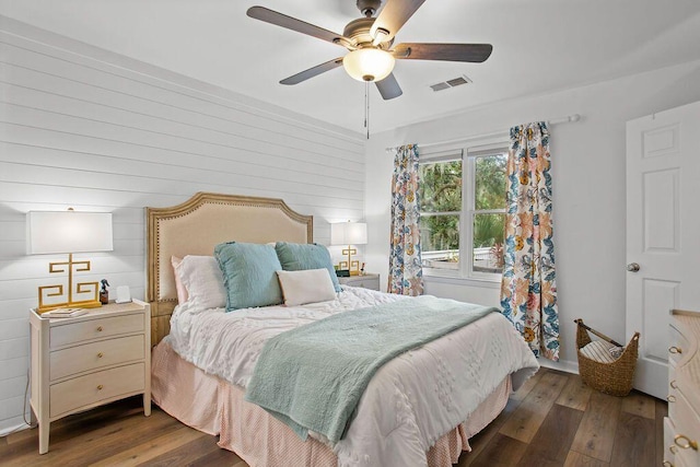 bedroom with wood walls, ceiling fan, and dark hardwood / wood-style floors