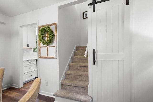 stairs with a barn door and hardwood / wood-style floors