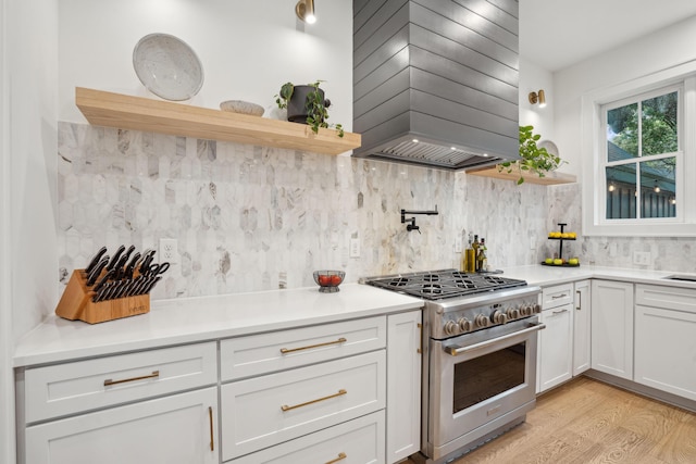 kitchen with wall chimney exhaust hood, open shelves, backsplash, and stainless steel range