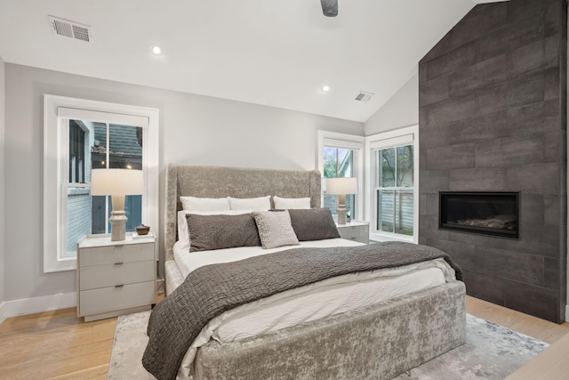 bedroom with light wood-type flooring, visible vents, and a fireplace