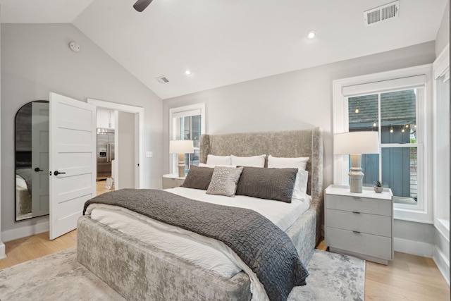 bedroom with stainless steel built in fridge, visible vents, light wood finished floors, and vaulted ceiling